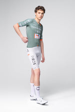 Male cyclist wearing Gobik Ineos Grenadiers sage green jersey and white bib shorts