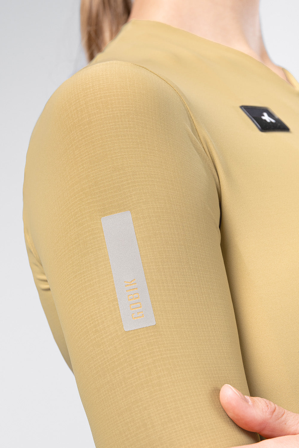 Detail shot of Gobik Avalon jersey sleeve showing reflective Gobik branding label in Keemun color