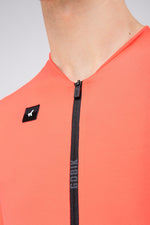 Close-up of Gobik Avalon Jersey zipper and brand logo patch in Lava coral color