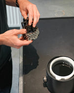 Hands holding black CeramicSpeed UFO chain hanger tool above hot wax container