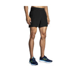 Man wearing black Brooks Sherpa 5-inch running shorts with blue sneakers