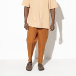 Person wearing brown Birkenstock Boston clogs with orange pants and beige shirt