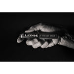 Hand holding Lezyne Pocket Drive mini bike pump in dramatic black and white studio photo