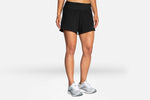 Woman wearing black Brooks Chaser 5-inch 2-in-1 athletic shorts with running shoes