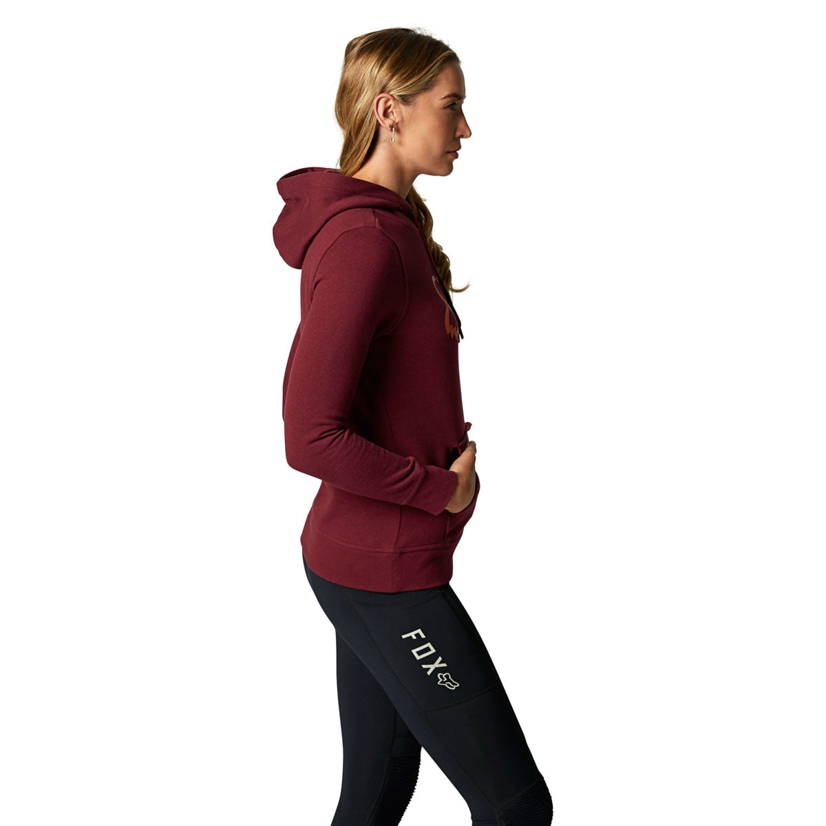 Woman wearing Fox Racing cranberry pullover fleece hoodie with black leggings, side profile view