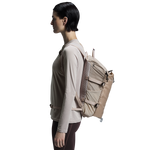 Woman wearing On Speed Pack 18L Lite backpack in cream sand color, side profile view