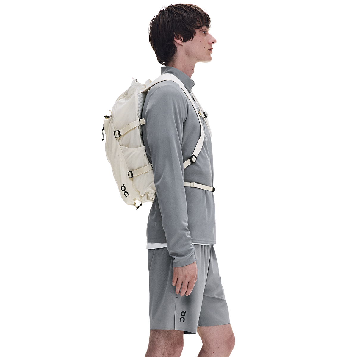 Male model wearing On Speed Pack 18L Lite backpack in cream with gray athletic outfit