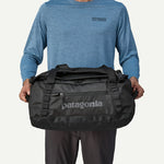 Man holding Patagonia Black Hole 40L Duffel bag in front of him, black
