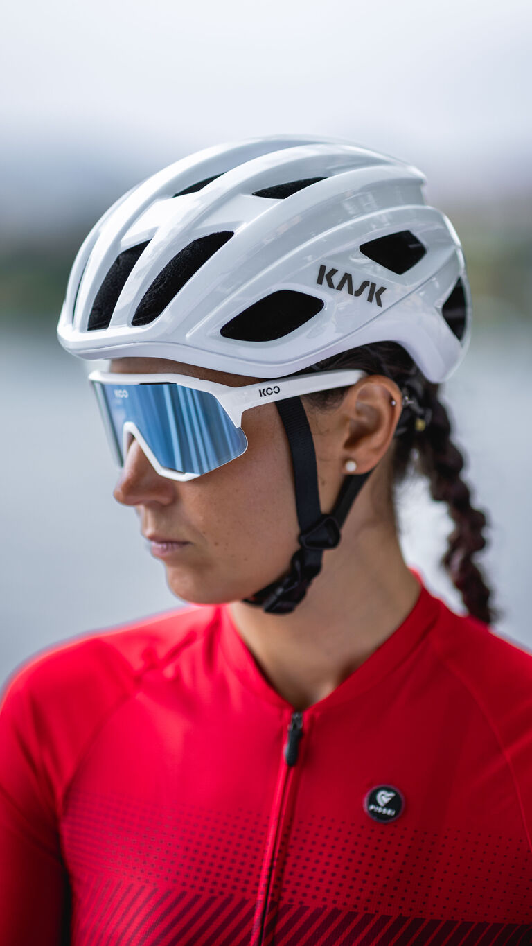 Woman wearing white Kask Mojito Cubed cycling helmet with blue sports sunglasses in profile view