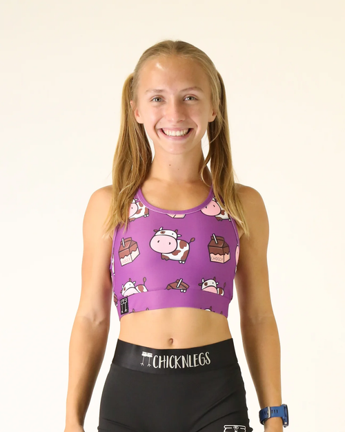 Female model wearing ChicknLegs purple Choccy Cows sports bra with cartoon print