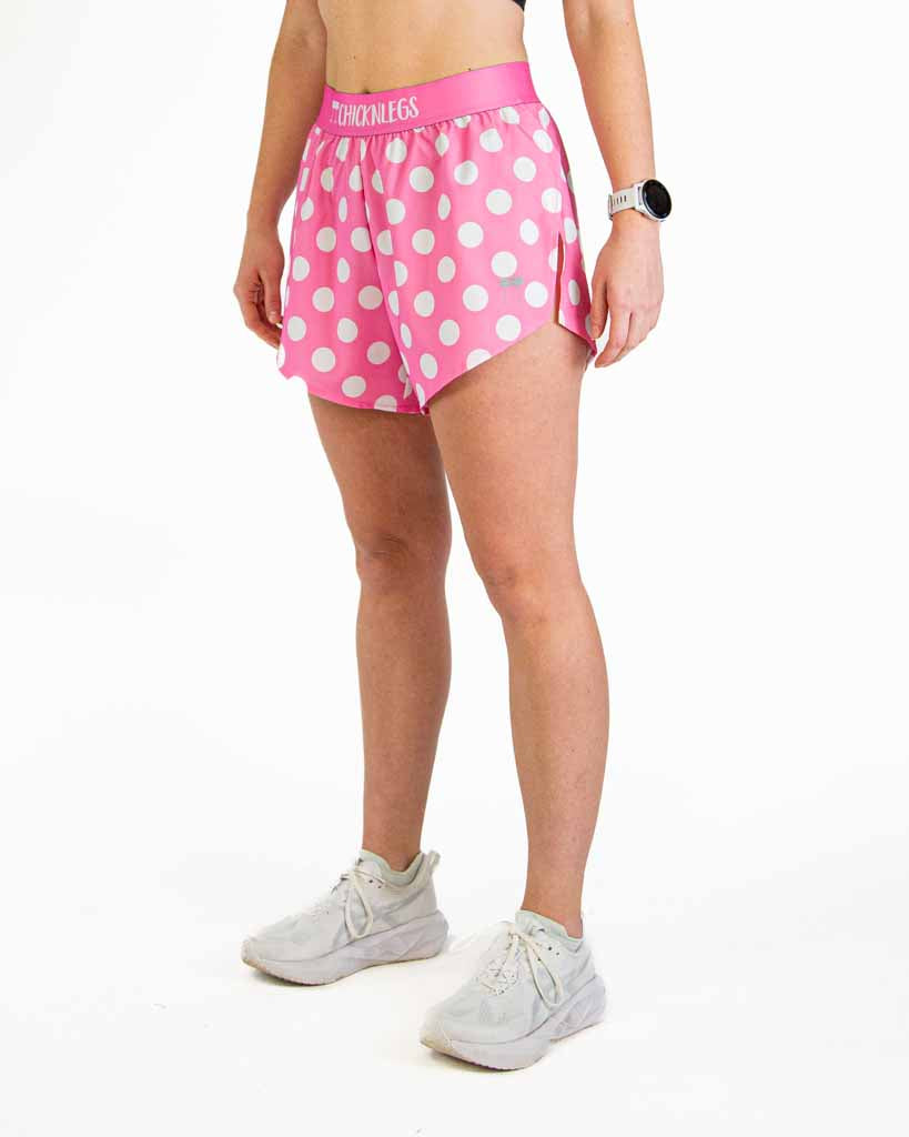Woman wearing pink polka dot split running shorts with white sneakers
