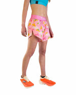Woman wearing pink ChicknLegs Princess Tiara split shorts with crown pattern and teal sports bra