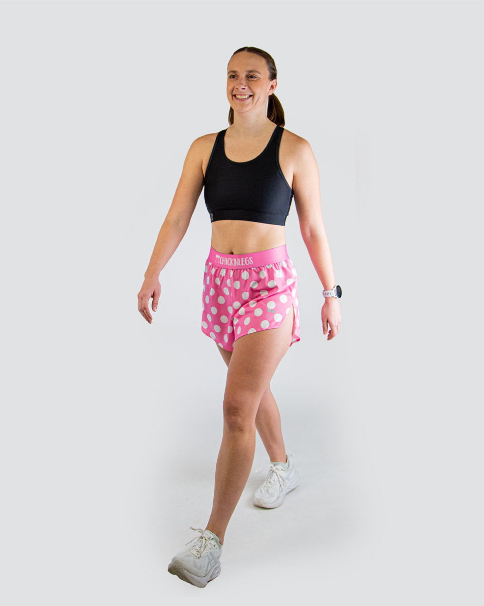 Woman wearing ChicknLegs pink polka dot split shorts with black sports bra