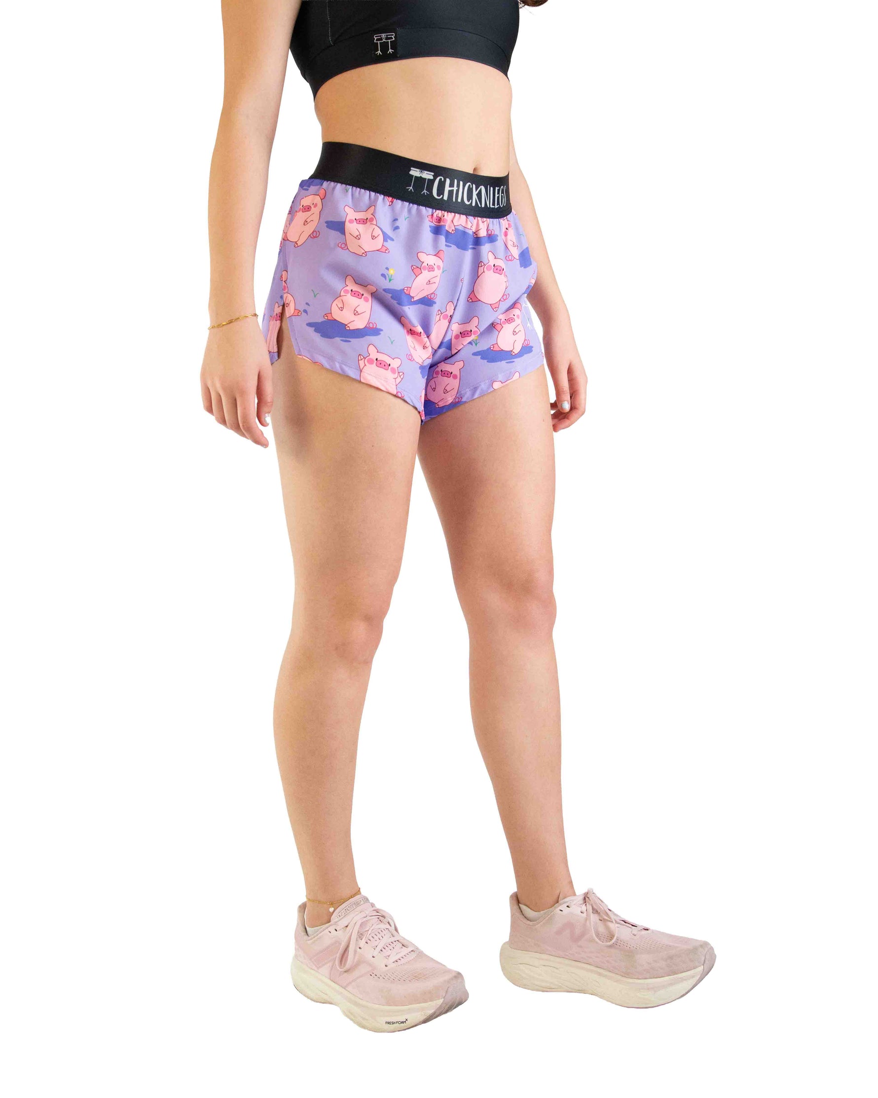 Woman wearing purple athletic shorts with pink pig pattern and black waistband