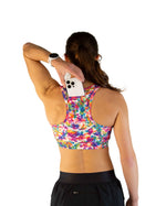 Woman wearing ChicknLegs tie-dye sports bra with colorful pattern, back view