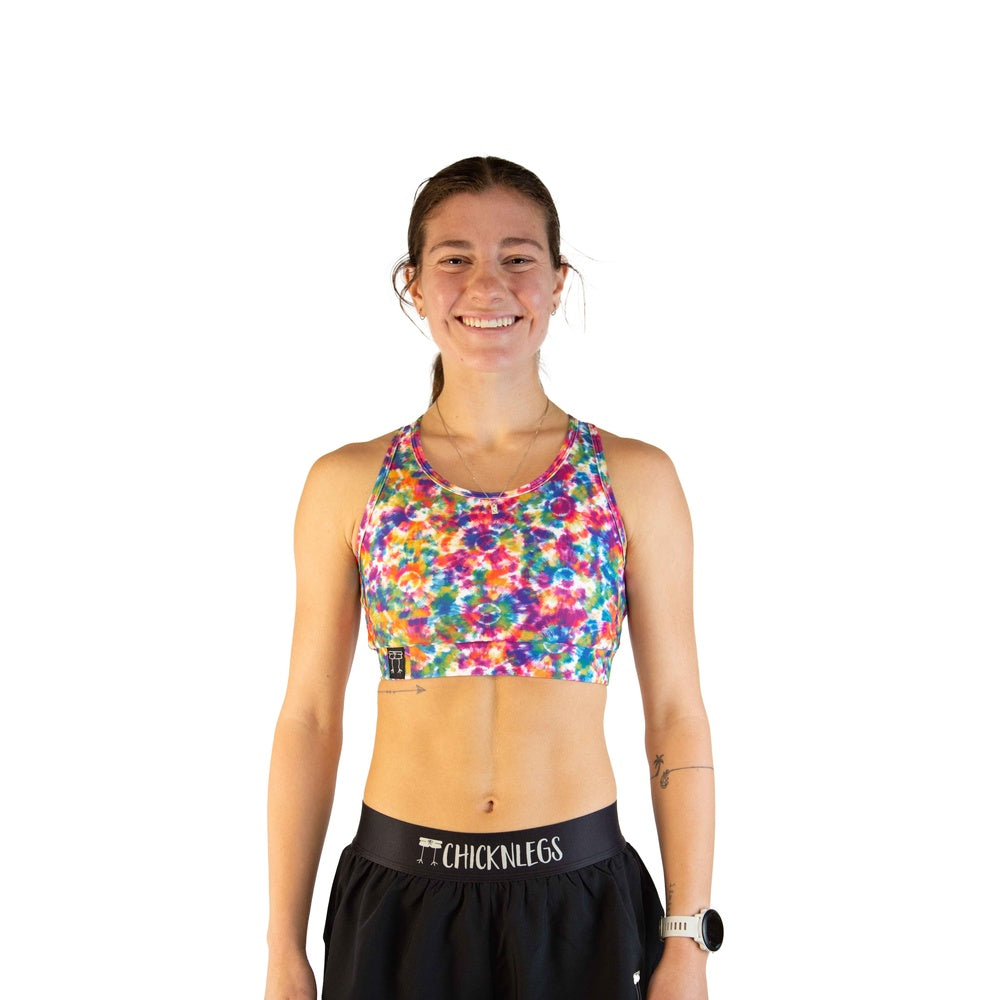 Woman wearing ChicknLegs tie-dye sports bra in vibrant rainbow kaleidoscope pattern