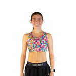 Woman wearing ChicknLegs tie-dye sports bra in vibrant rainbow kaleidoscope pattern