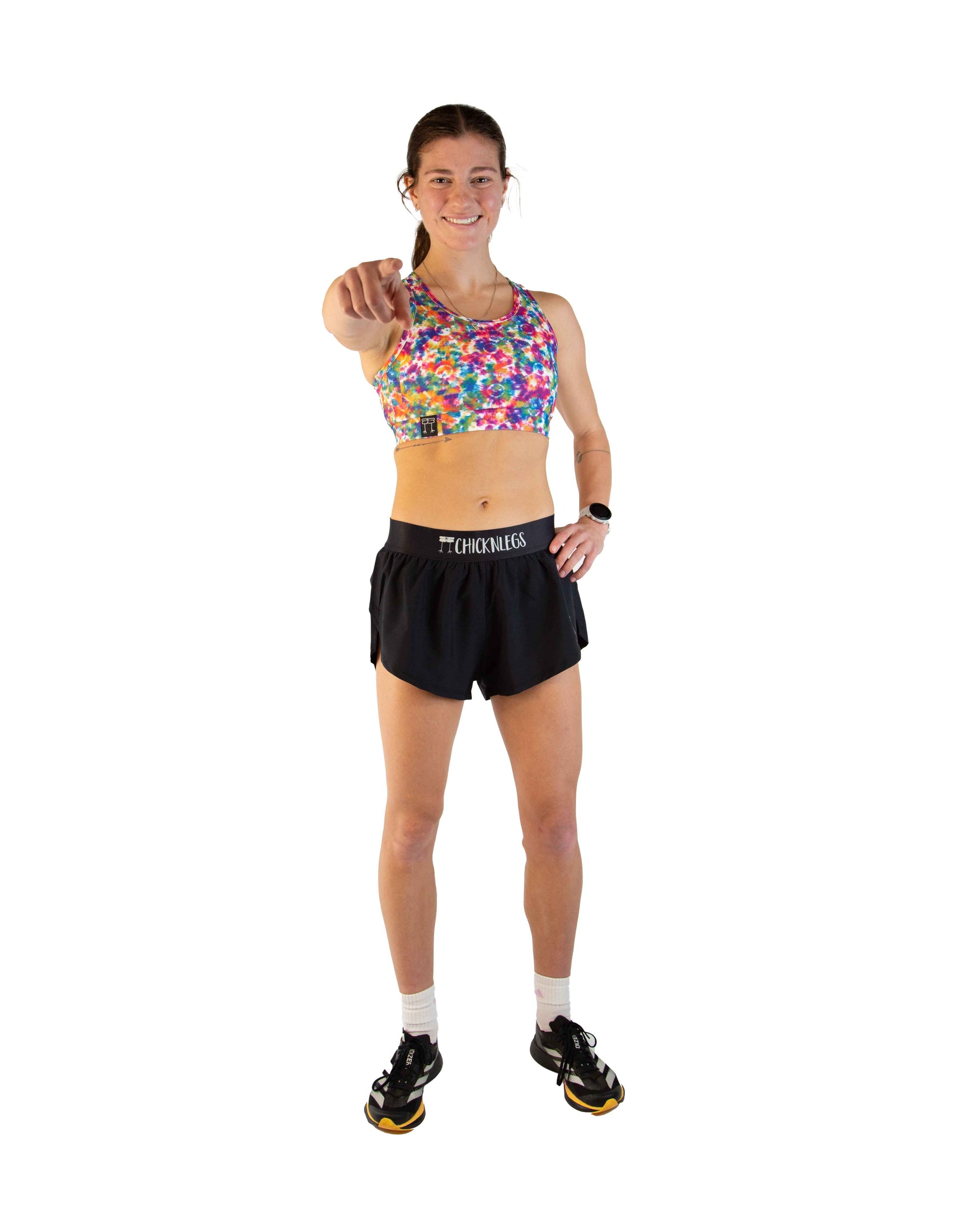 Woman wearing ChicknLegs tie-dye sports bra and black shorts in studio photo