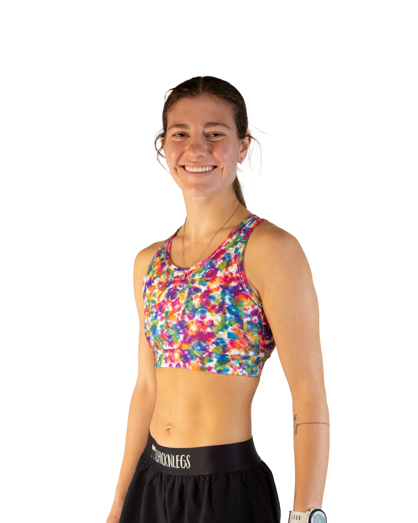 Woman wearing colorful tie-dye sports bra with rainbow pattern and black shorts