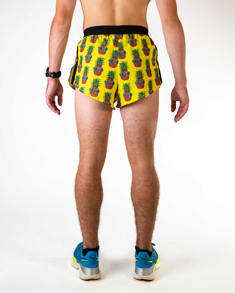 Back view of male model wearing ChicknLegs yellow pineapple print 2-inch split running shorts