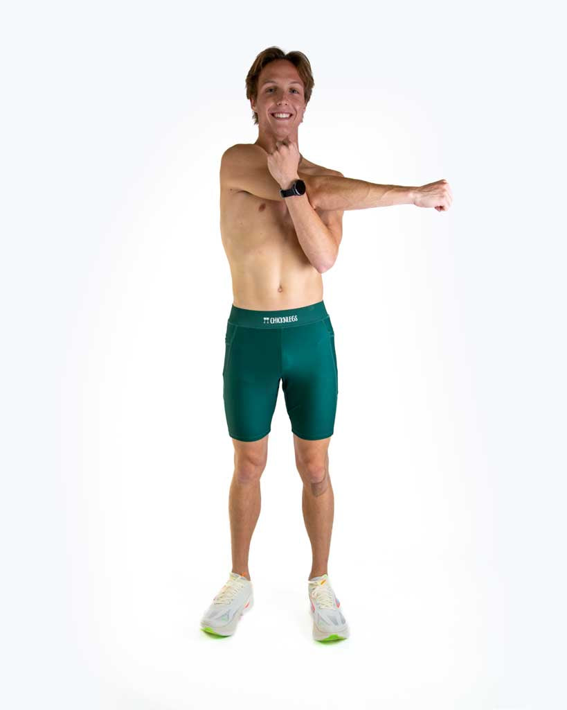 Athletic man wearing forest green ChicknLegs compression shorts against white studio background