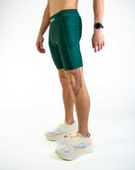 Man wearing forest green athletic shorts with professional running shoes on white background