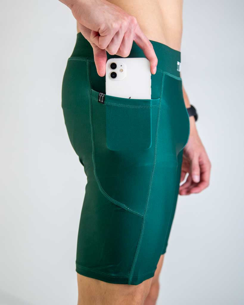 Person wearing forest green athletic shorts with phone in side pocket