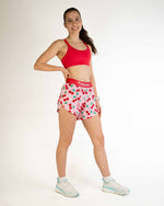 Female model wearing ChicknLegs 4-inch split running shorts in cherry print pattern