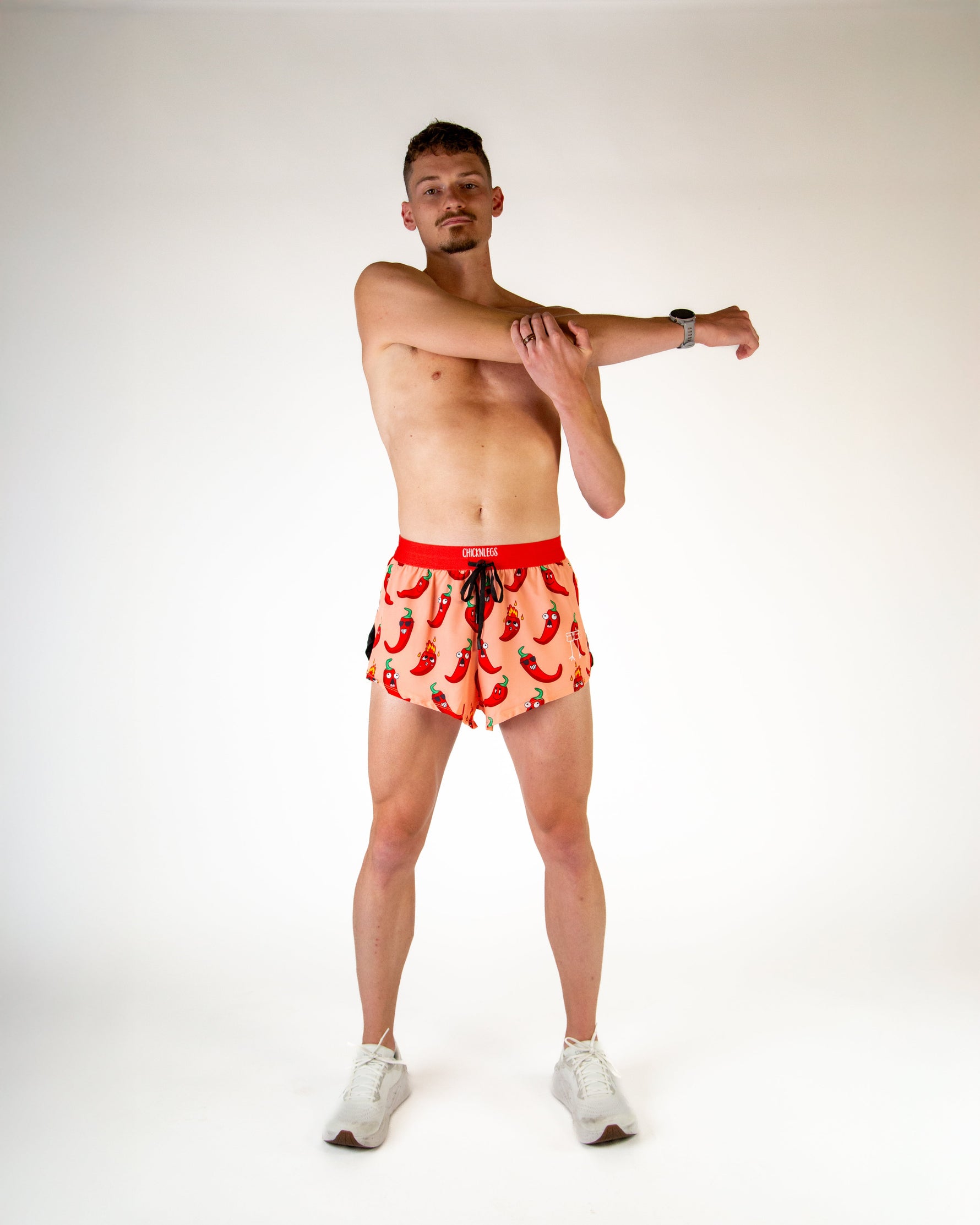 Man wearing ChicknLegs red chili pepper print split shorts in studio setting