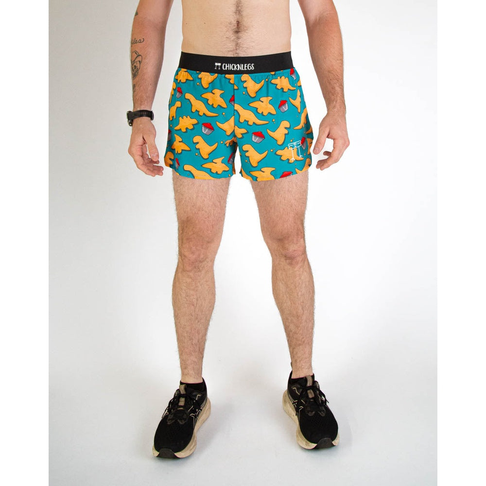 Man wearing teal ChicknLegs shorts with orange dinosaur nuggets pattern and black waistband