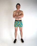 Man wearing blue ChicknLegs shorts with orange nugget pattern against white background