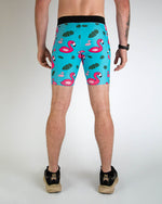 Man wearing turquoise blue half tights with pink flamingo and tropical leaf pattern