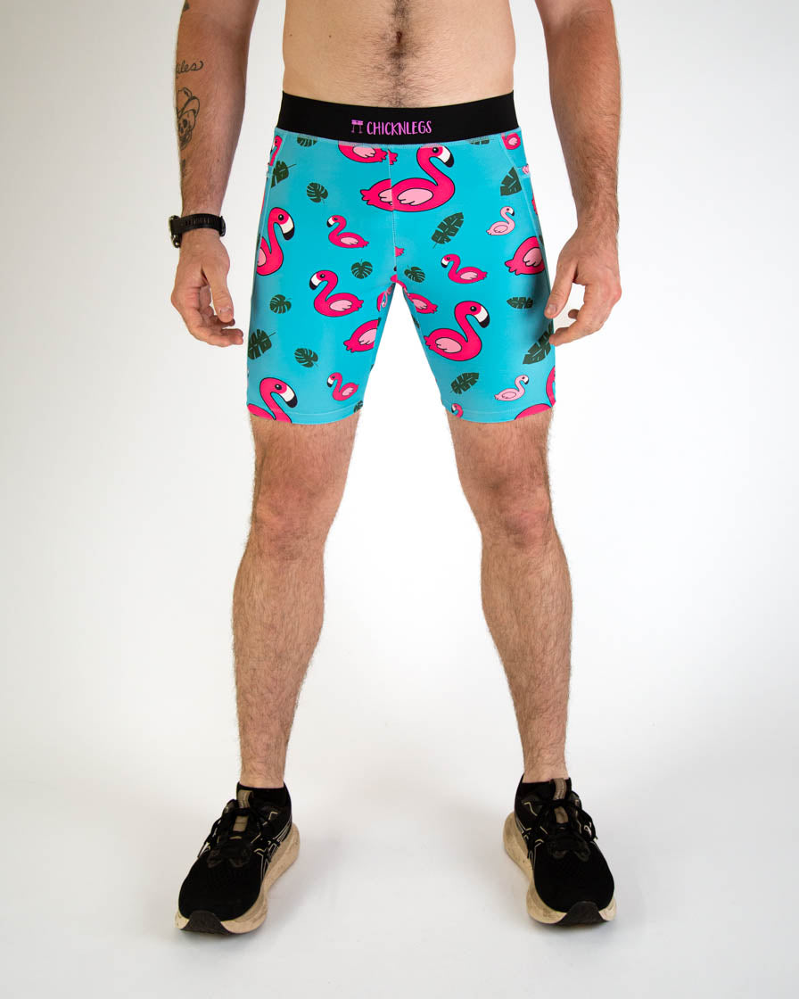 Man wearing turquoise blue compression shorts with pink flamingo and tropical leaf print