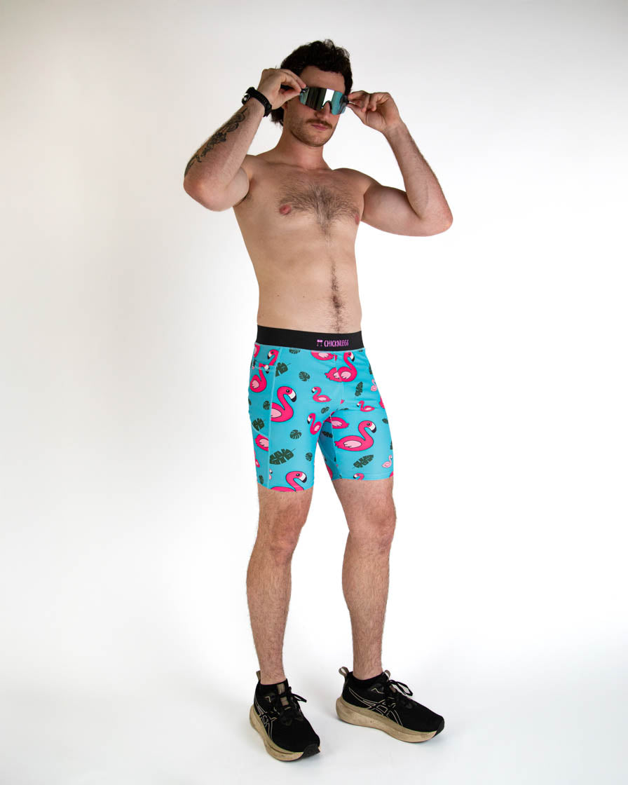 Man wearing turquoise blue shorts with pink flamingo pattern and sunglasses