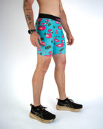 Man wearing turquoise blue shorts with pink flamingo pattern and black waistband