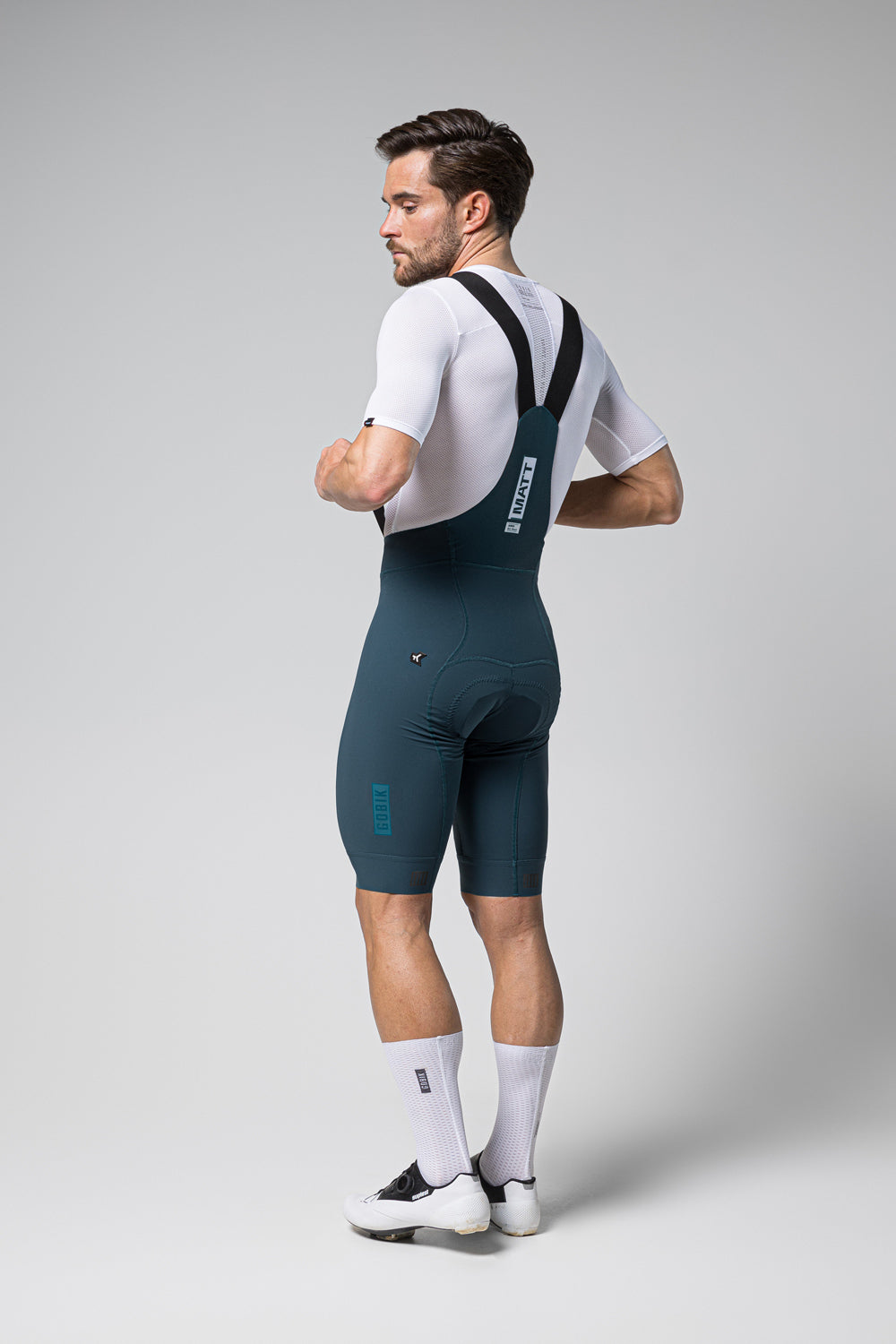 Man wearing Gobik Matt 2.0 bib shorts in dark teal with white jersey