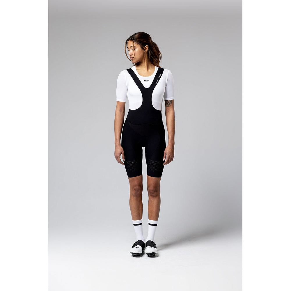 Woman wearing black Gobik Ultralite bib shorts with white jersey in studio setting