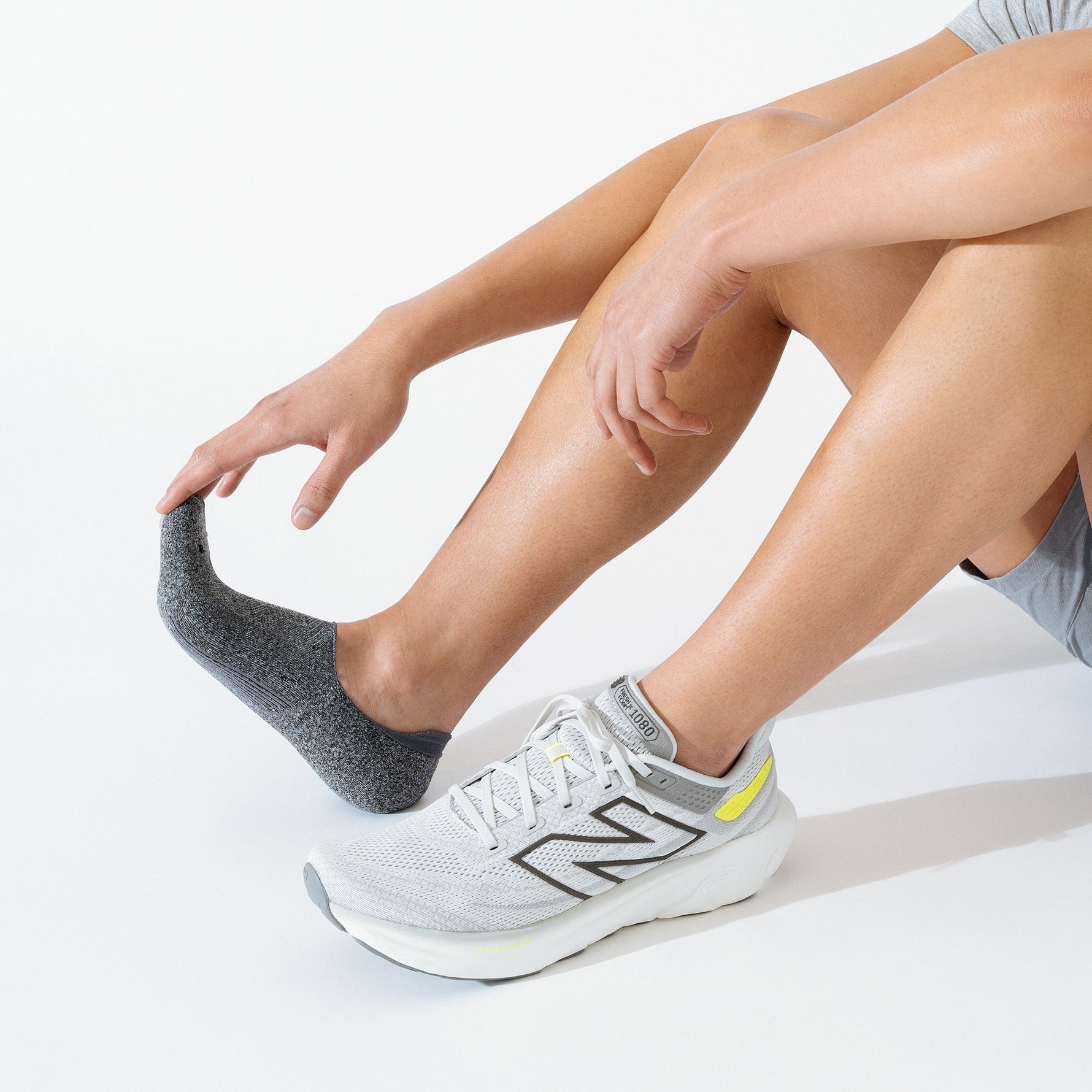 Person wearing Feetures Elite Light Cushion Invisible no-show socks in charcoal black with New Balance shoes