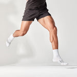 Athletic runner wearing white Feetures Elite Ultra Light Mini Crew socks mid-stride