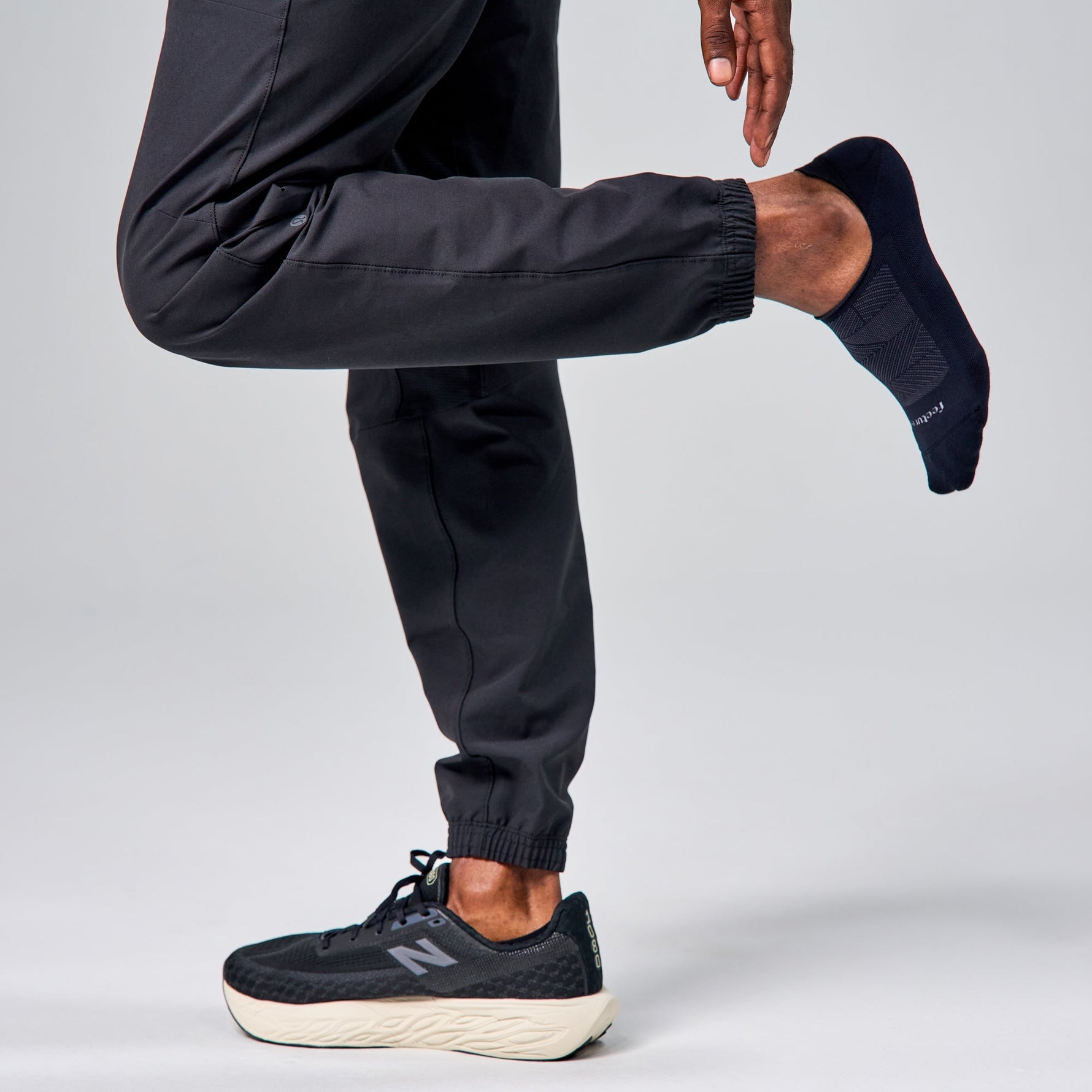 Model wearing Feetures Elite Light Cushion Invisible black no-show socks with New Balance sneakers