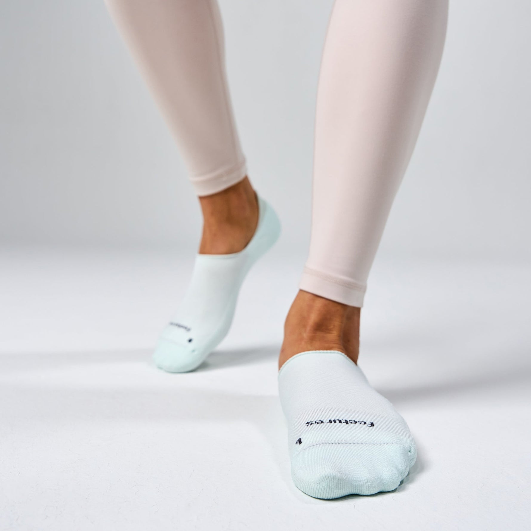 Feetures Elite Light Cushion Invisible no-show socks in mint on model wearing pink leggings