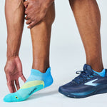Feetures Elite Light Cushion Tab sock in Mint Chip colorway shown on athlete's foot beside Brooks running shoe