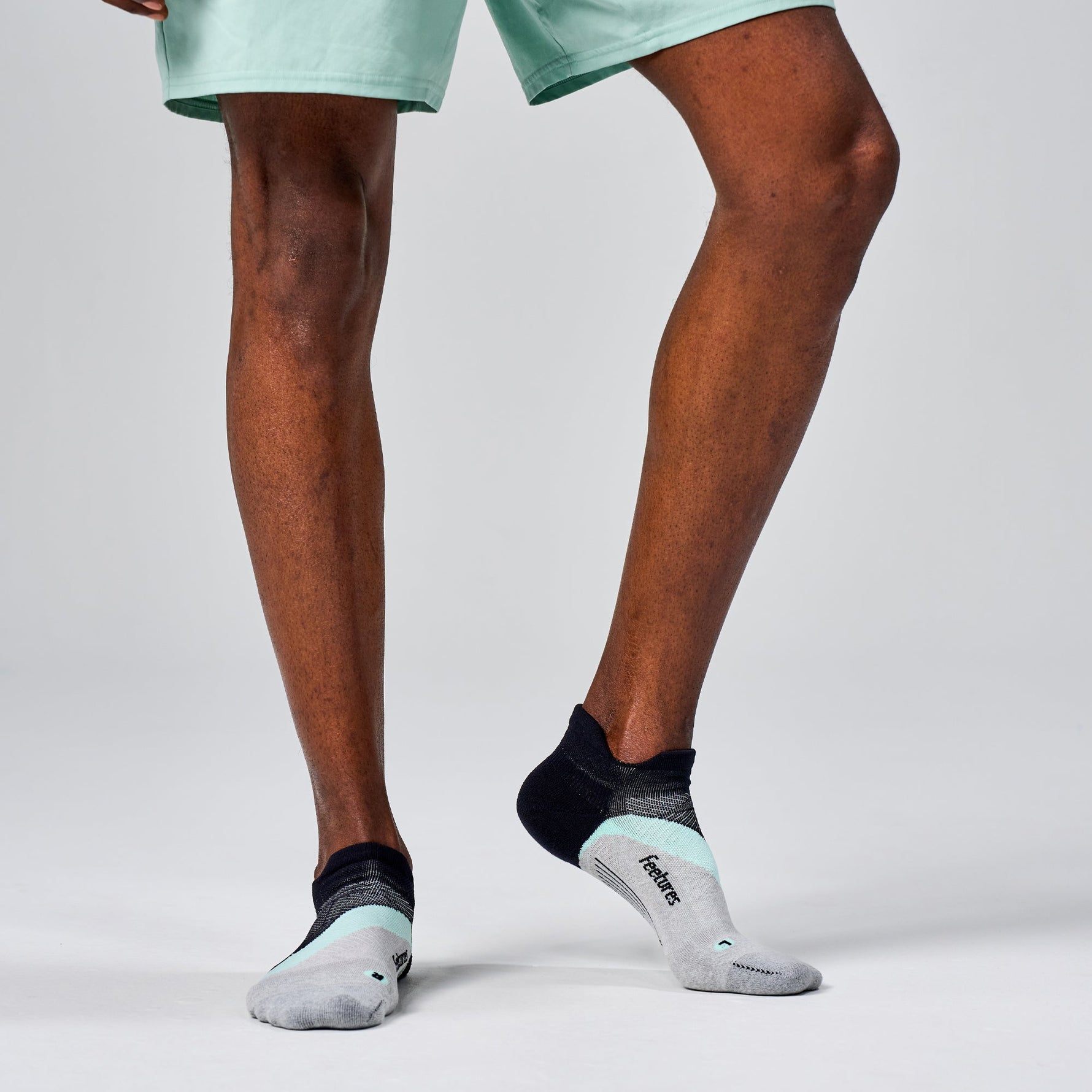 Person wearing Feetures Elite Light Cushion Tab socks in Stone Ivy colorway with mint green shorts