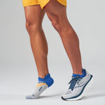 Person wearing Feetures Elite Light Cushion Tab socks in blue colorblock pattern with running shoes