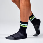 Feetures Elite Ultra Light Mini Crew black socks with neon yellow stripe on model