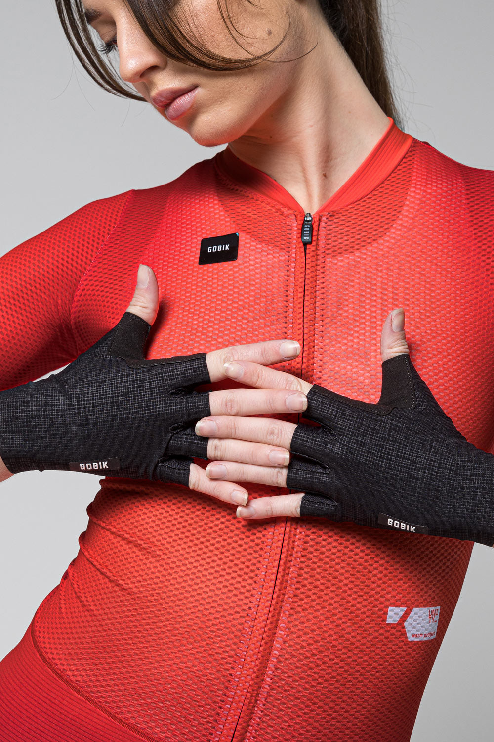 Woman wearing black Gobik fingerless cycling gloves with red cycling jersey