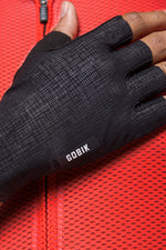 Black Gobik cycling gloves with textured palm grip on red background