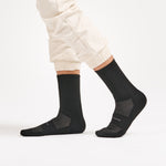 Feetures High Performance Max Cushion Crew socks in black worn by model with white pants