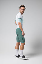 Male model wearing Gobik Brooklyn Aerosuit in sage green cycling outfit with white accents
