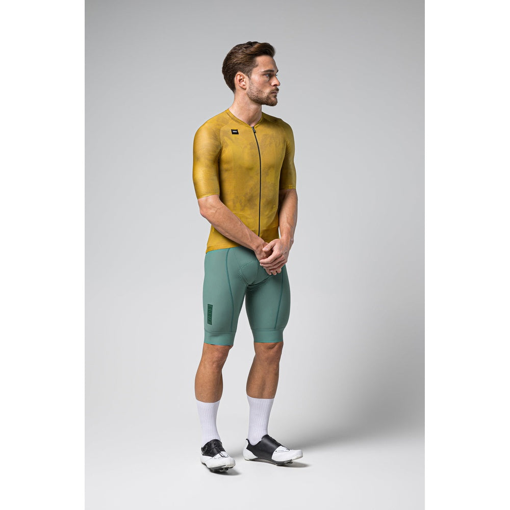 Male model wearing Gobik Infinity cycling jersey in ginger yellow with green shorts